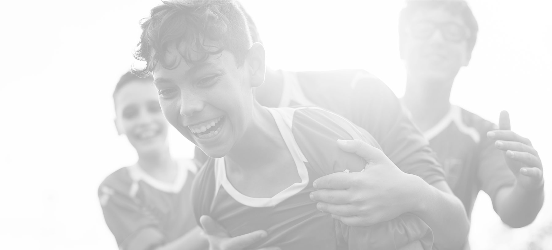 Group of young athletes smiling and enjoying a soccer game together, showing teamwork and excitement.